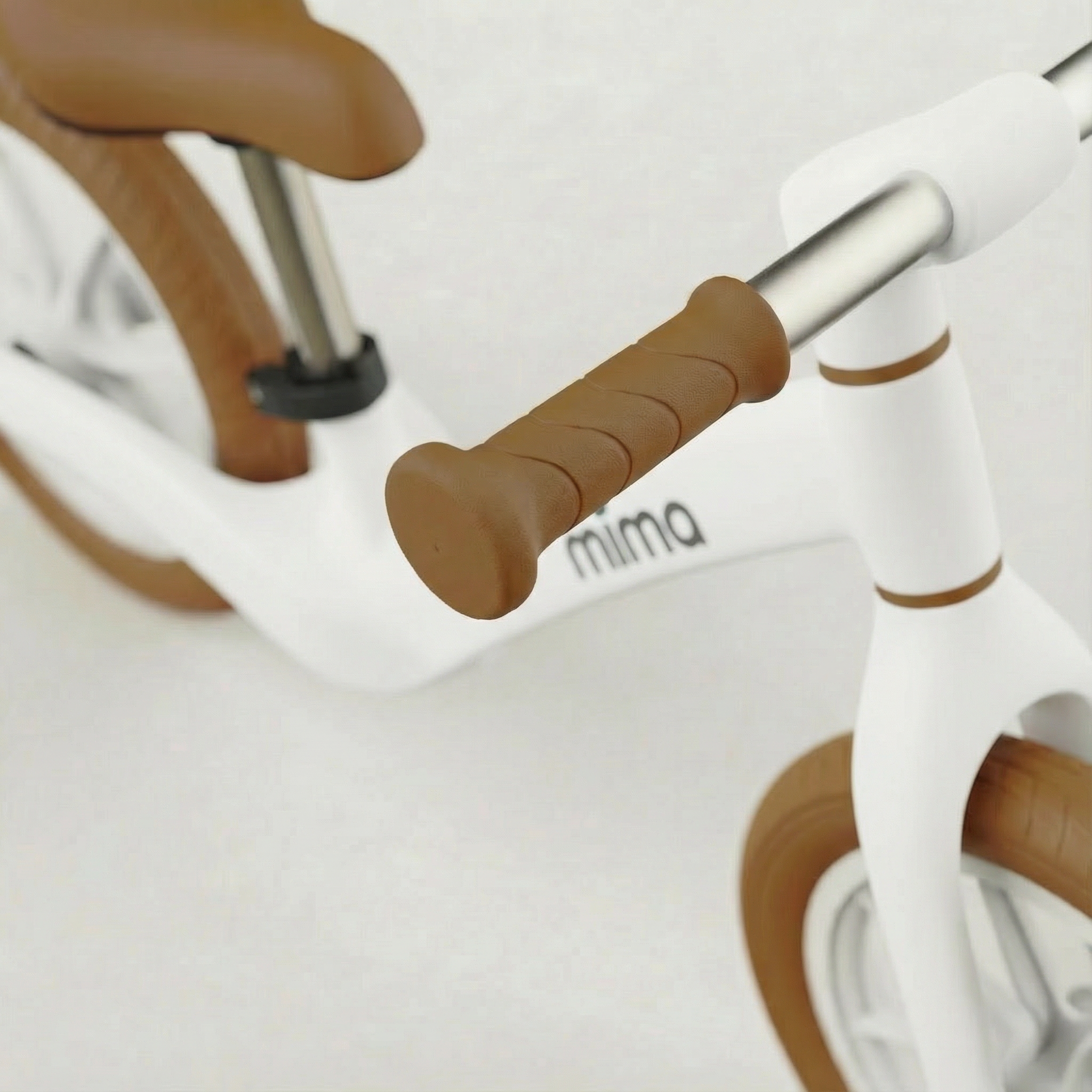 Close-up of a white bicycle with handlebar grips and 'mima' branding on a white background