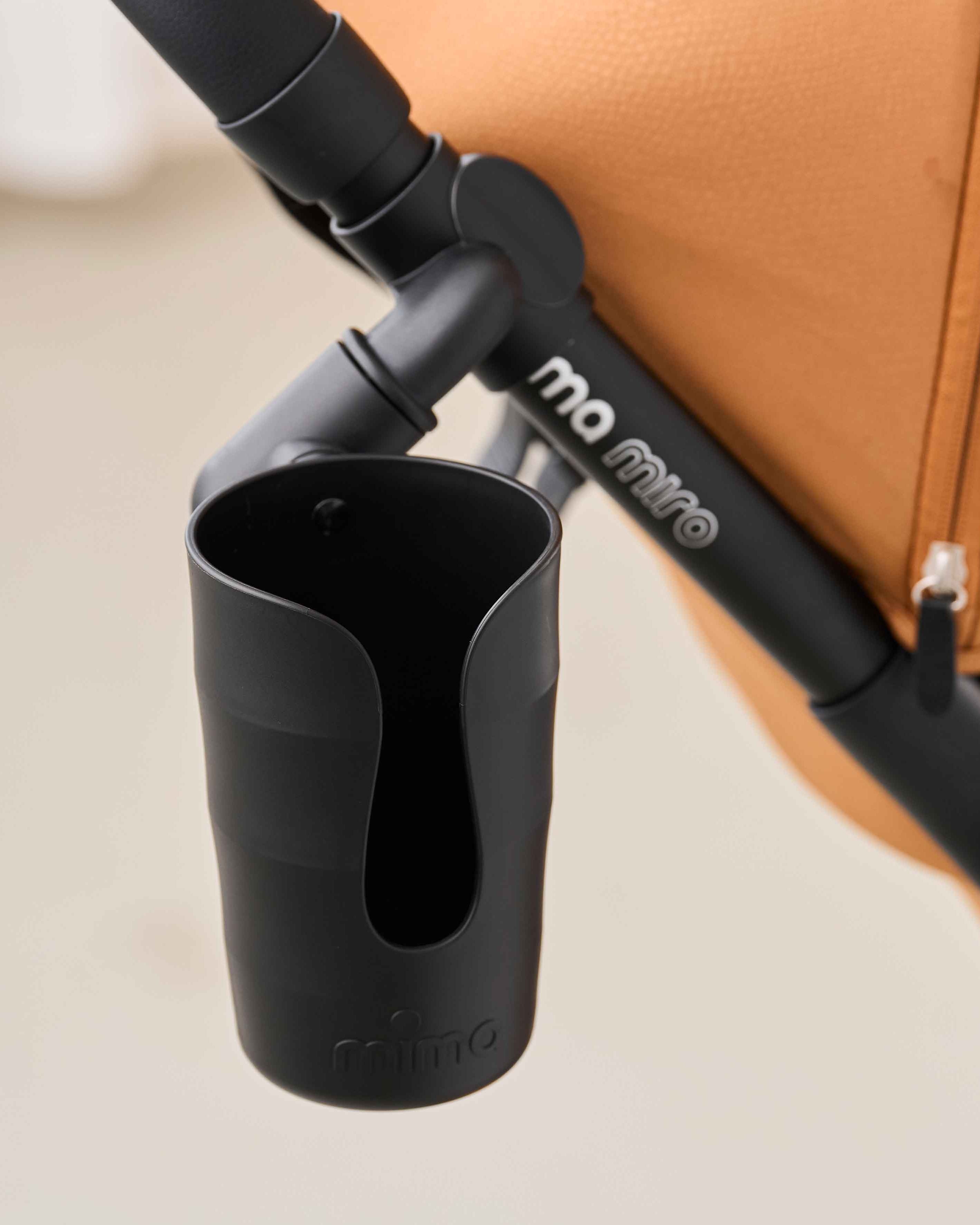 mima cup holder with clip attached to a miro stroller in mocha colour, side view.