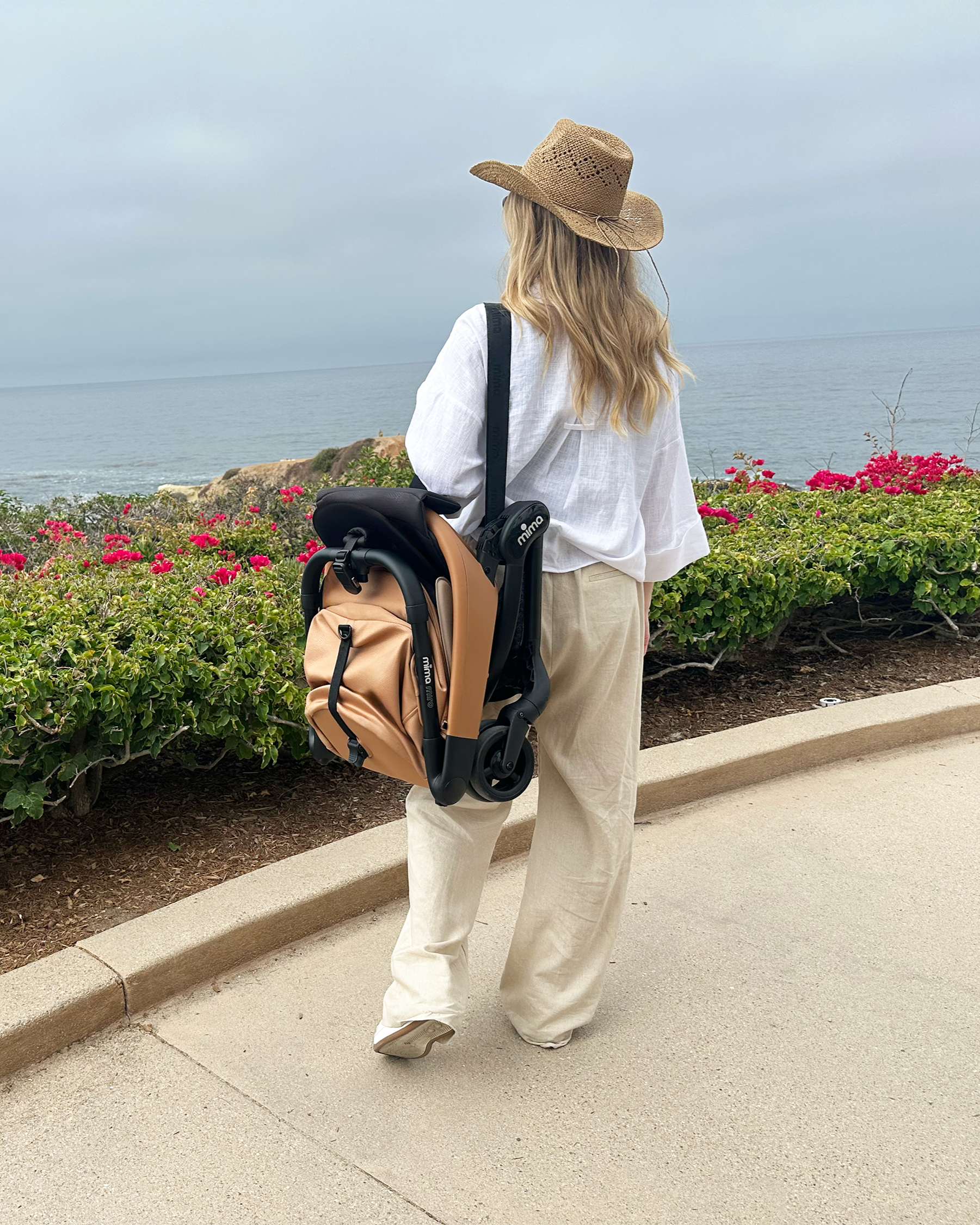 Mother carrying in her shoulder mima miro mocha on a beach walk.