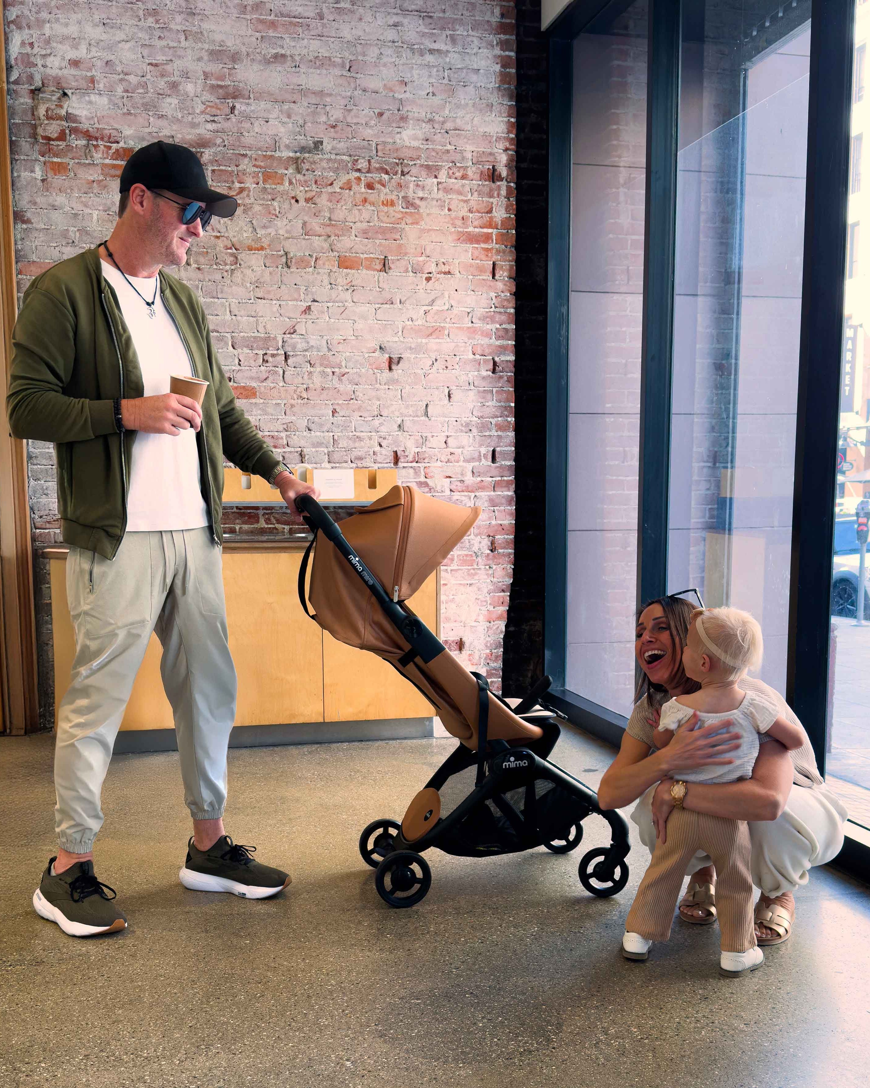 family indoors near a brick wall with toddler and mima miro stroller in mocha