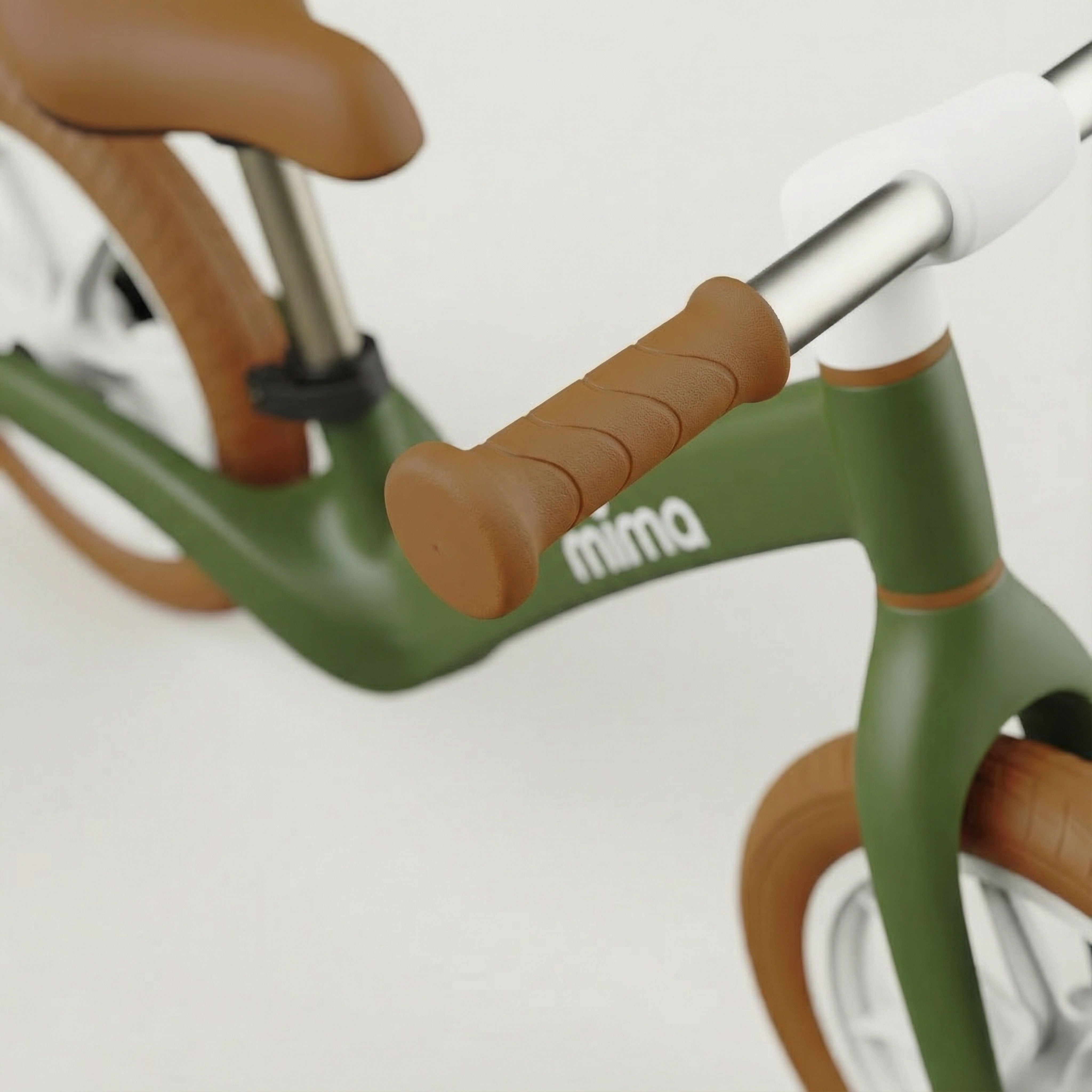 Close-up of a children's balance bike with brown handlebar grips and green frame